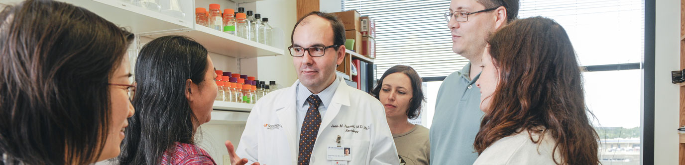 A male faculty member talks with five trainees