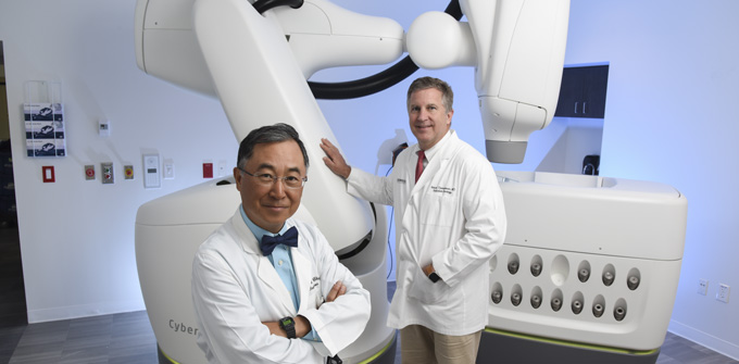 Two male doctors stand in front of large equipment