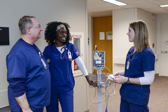 A man and two women talk in a hallway