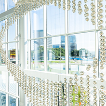 A hanging arrangement of glass bulbs arranged to leave a hole in the middle, framing the UTSW buildings outside the window.