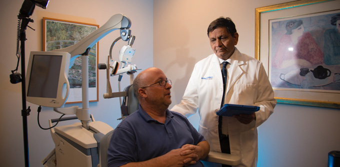 Madhukar Trivedi, M.D., talks to a male patient who sits in a chair